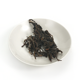 200g presents tightly pressed raw tea cake with visible whole buds and young leaves