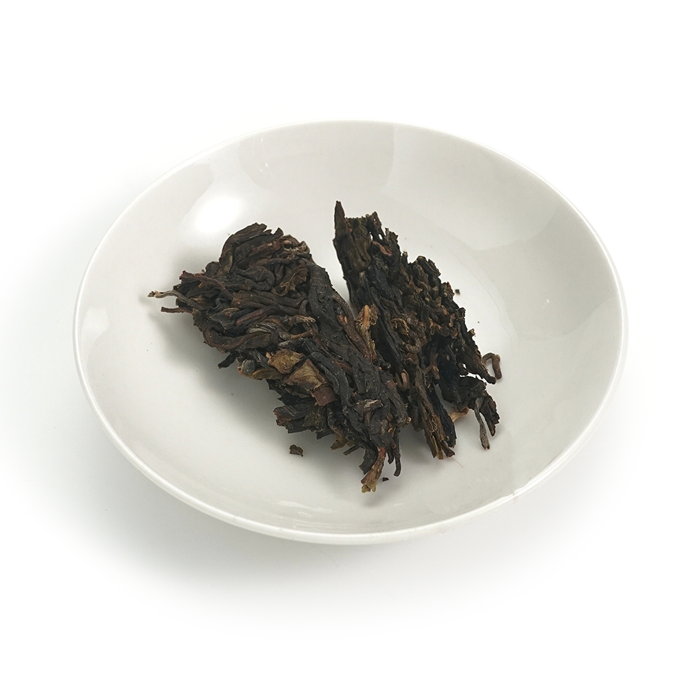 Aged Raw Puerh (Sheng) tea cake from 2012 by Fengpai, displaying aged brownish-green leaves.