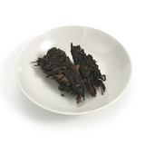 Aged Raw Puerh (Sheng) tea cake from 2012 by Fengpai, displaying aged brownish-green leaves.