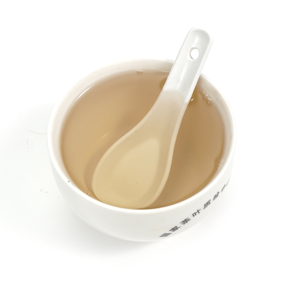 Translucent and clear tea infusion of Yue Guang Bai showing its delicate honey-gold color.