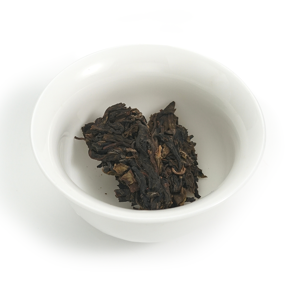 Close-up of the 2012 Mellow Aged Raw Pu’er (Fengpai) 357g cake surface with visible tea buds.