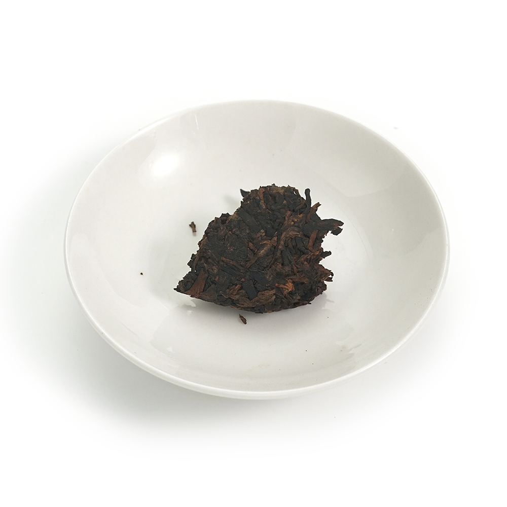 Close-up of the 2016 Decade-Aged Ripe Pu’er Cake surface, displaying mature leaves and golden buds.